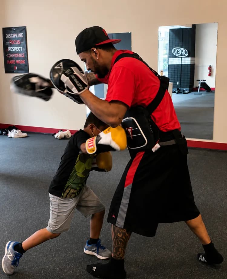 Coach doing pad work with an athlete at Romero's Boxing School