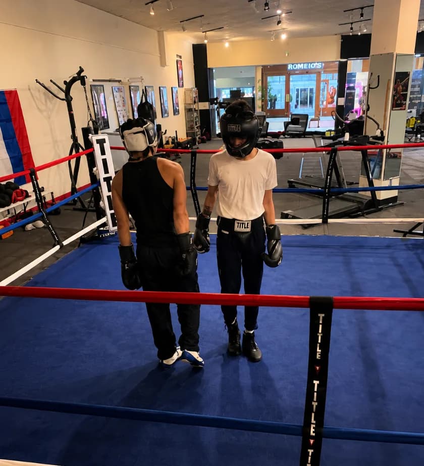 Two athletes in headgear ready to spar inside the Romero's Boxing School ring